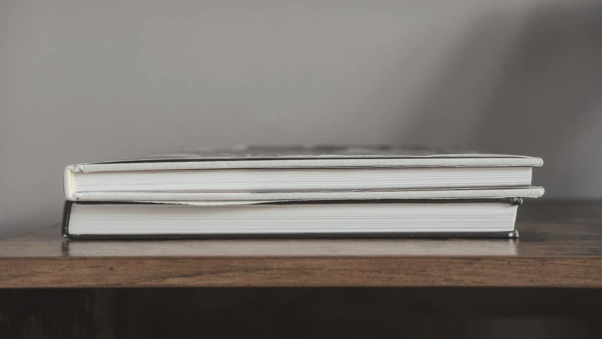 Two hardback books stacked on a wooden table