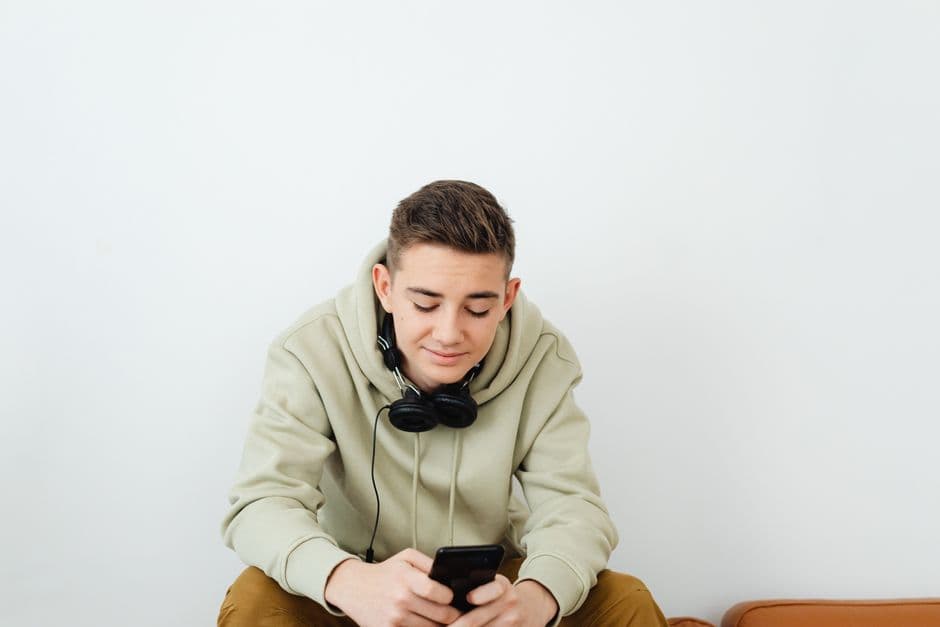 A young person wearing headphones, using a phone