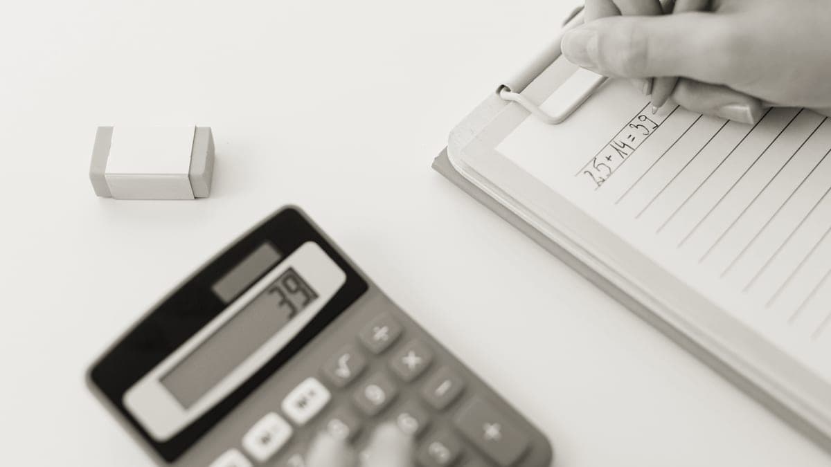 A calculator, notebook and pen on a wooden desk
