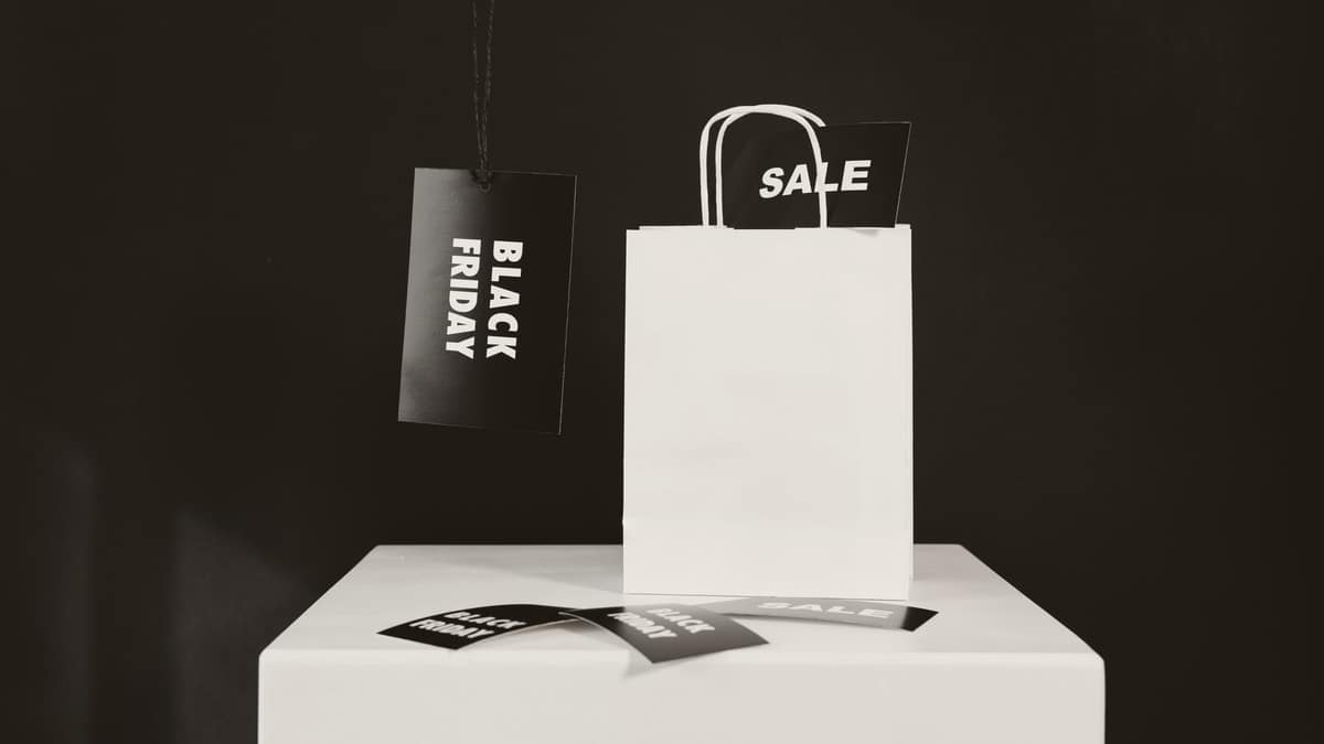 Black Friday and sale tags beside a white paper shopping bag on a dark background