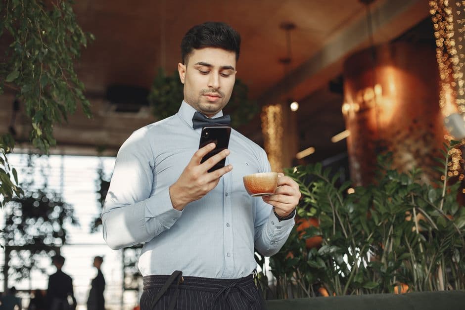 A person checking a phone over coffee in a cafe