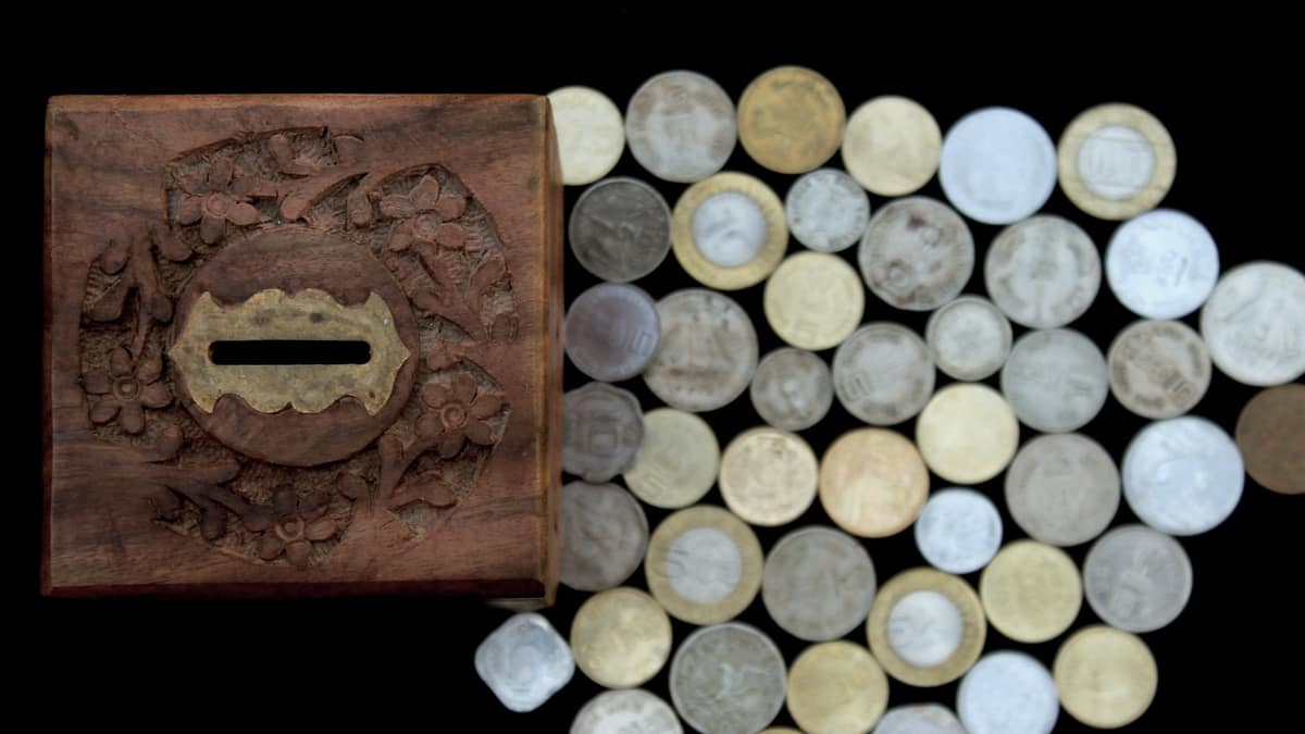 Coins stacked beside a small wooden box on a table