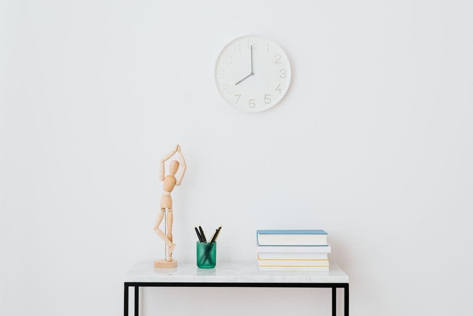 A clock and a few books on a white shelf