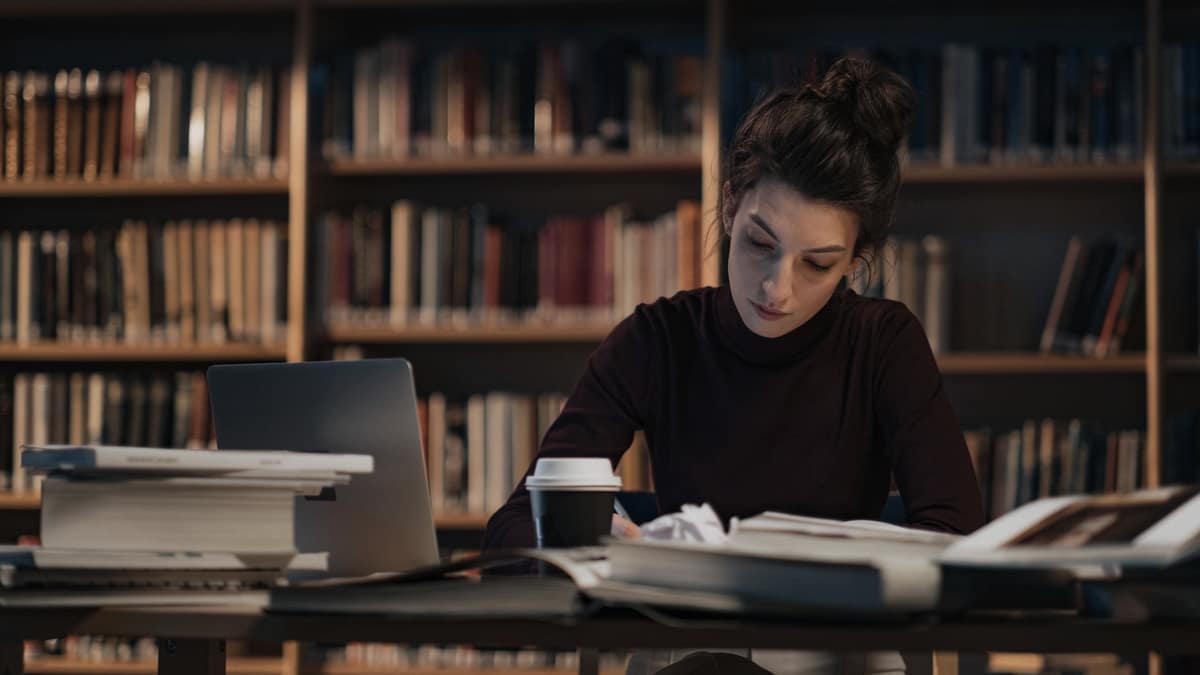 A student working with a laptop and open books