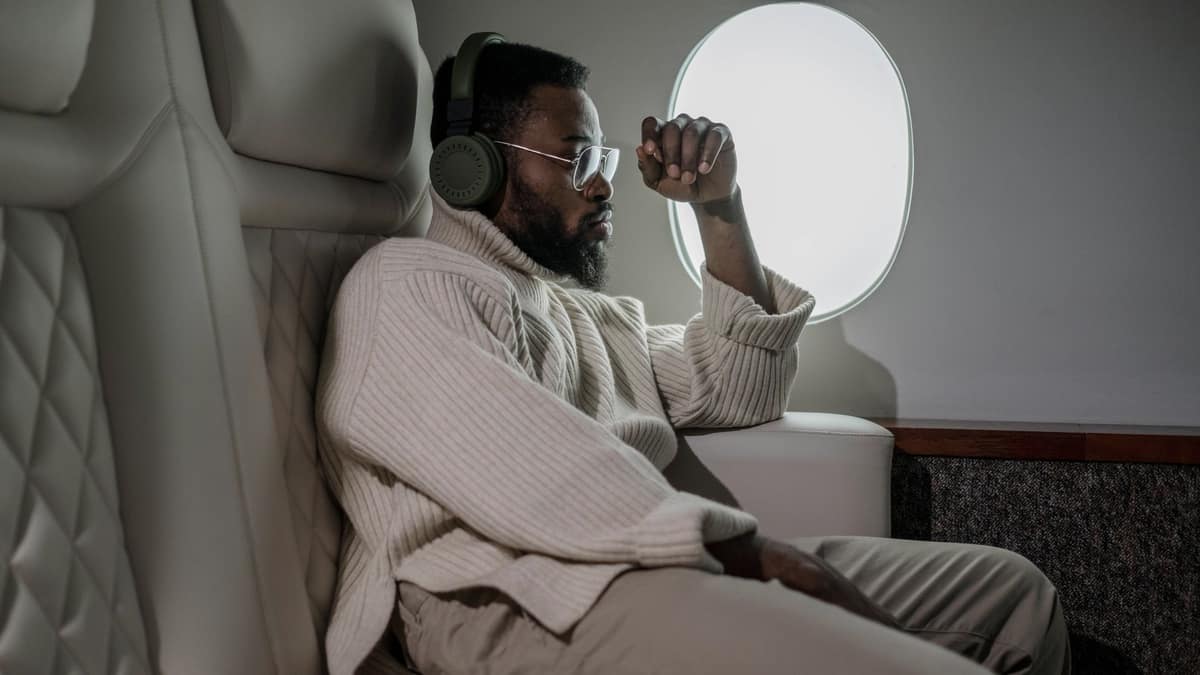 A traveler wearing headphones beside an airplane window