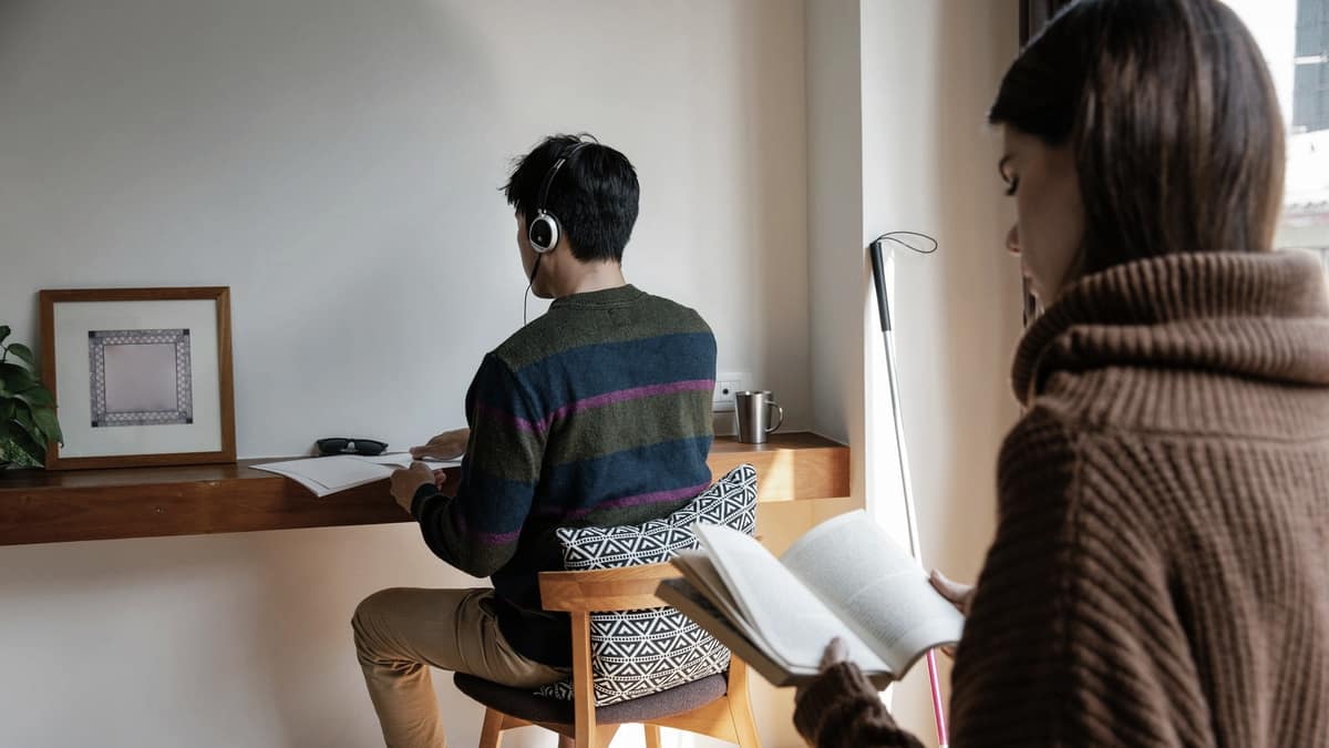 A person concentrating with headphones on at a sunlit desk
