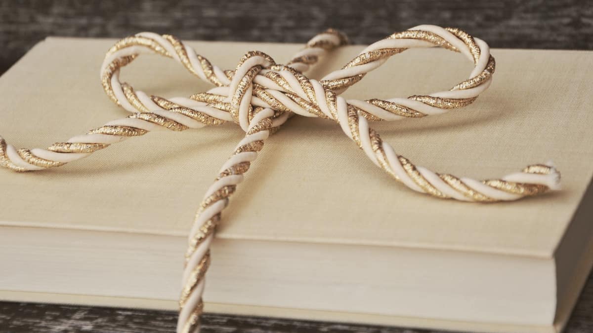 A wrapped book tied with a twisted gold and white ribbon