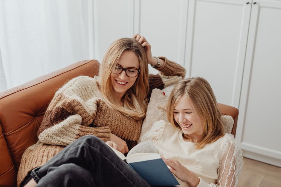 Two people reading together on a sofa