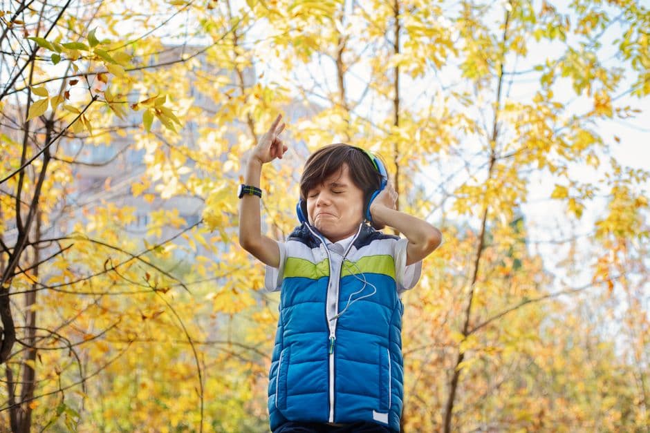 A boy wearing headphones in a park in autumn