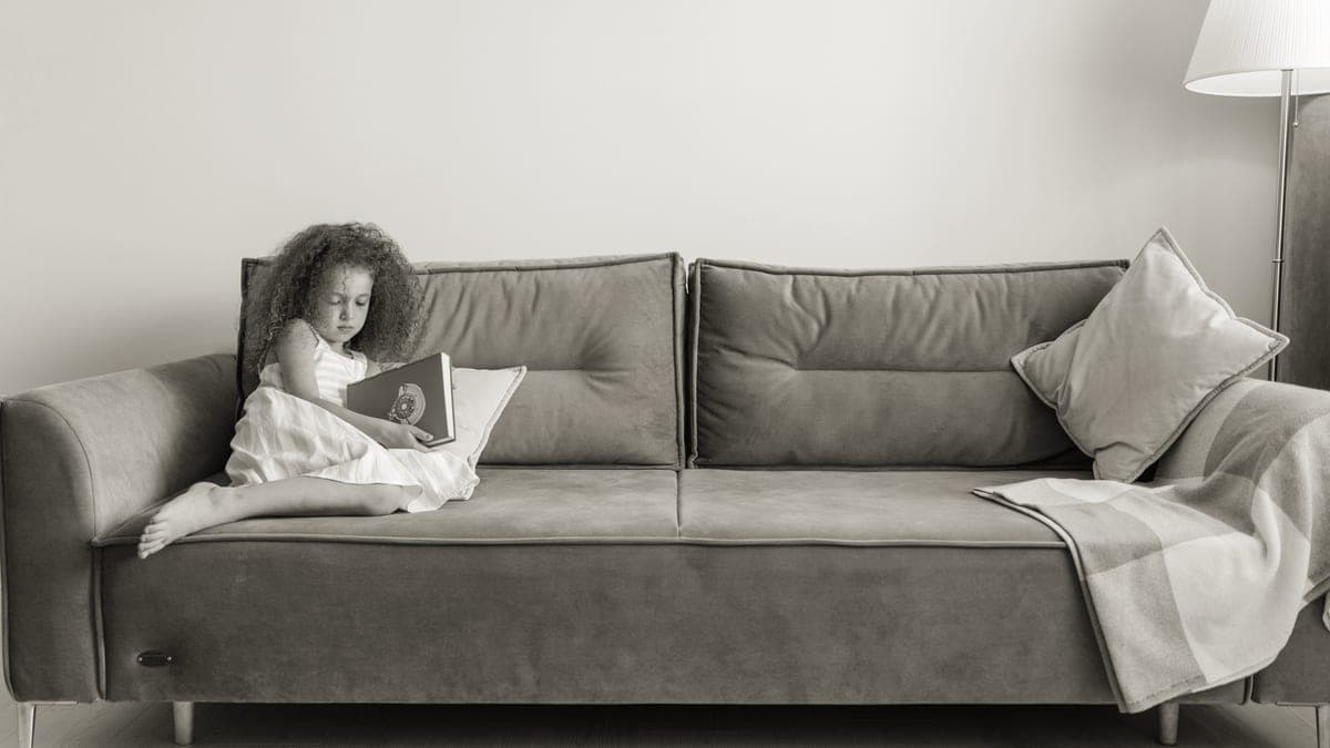 A child reading a book while sitting on a sofa