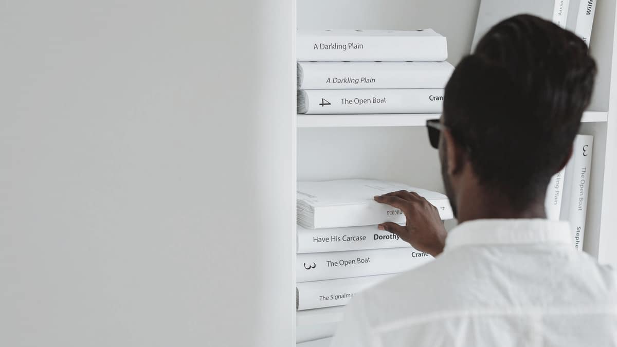 A person browsing books on a white shelf