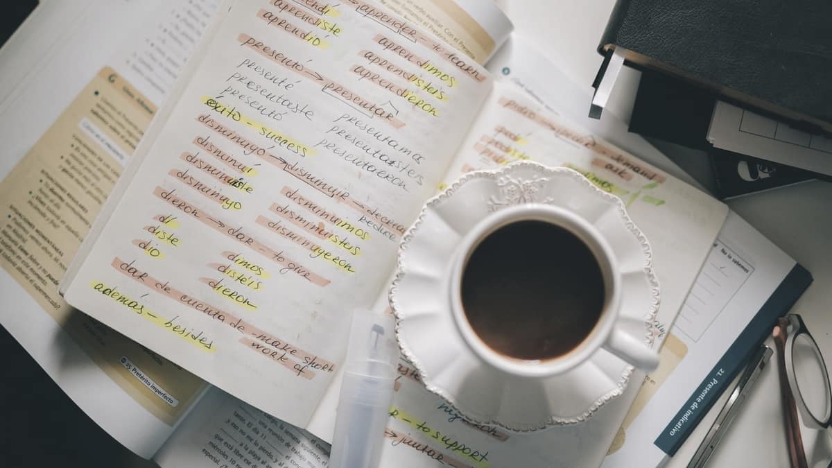 Handwritten Spanish study notes beside a cup of coffee