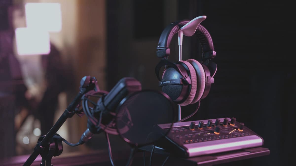 A studio microphone and headphones on a mixing desk