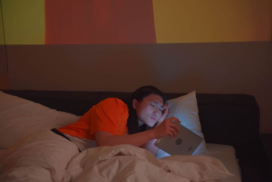 Someone reading on a tablet while reclining on a bed at night