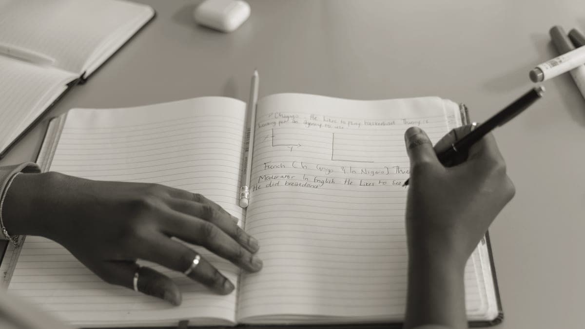 A person writing notes in a journal at a desk