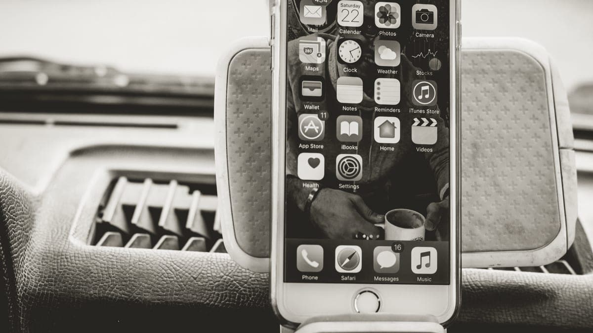 A smartphone and headphones resting on a car dashboard