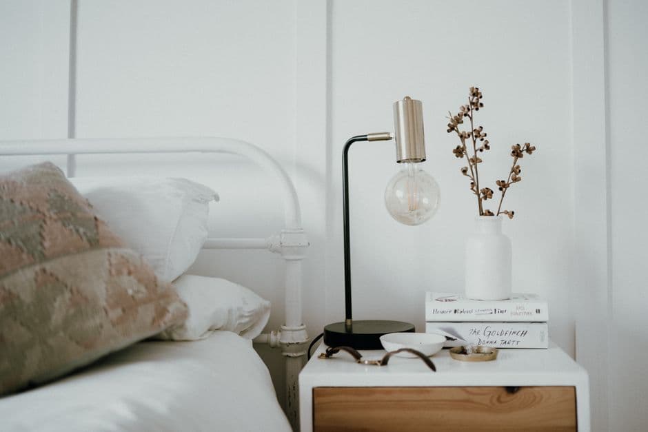 A bedside table with a lamp and a small stack of books
