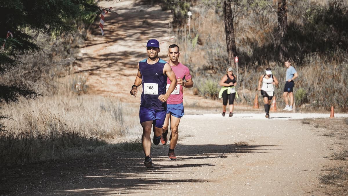 Runners on a dirt trail through woodland