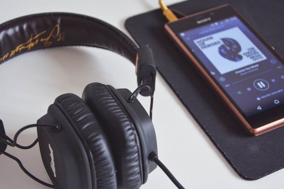 Headphones beside a smartphone playing music on a desk