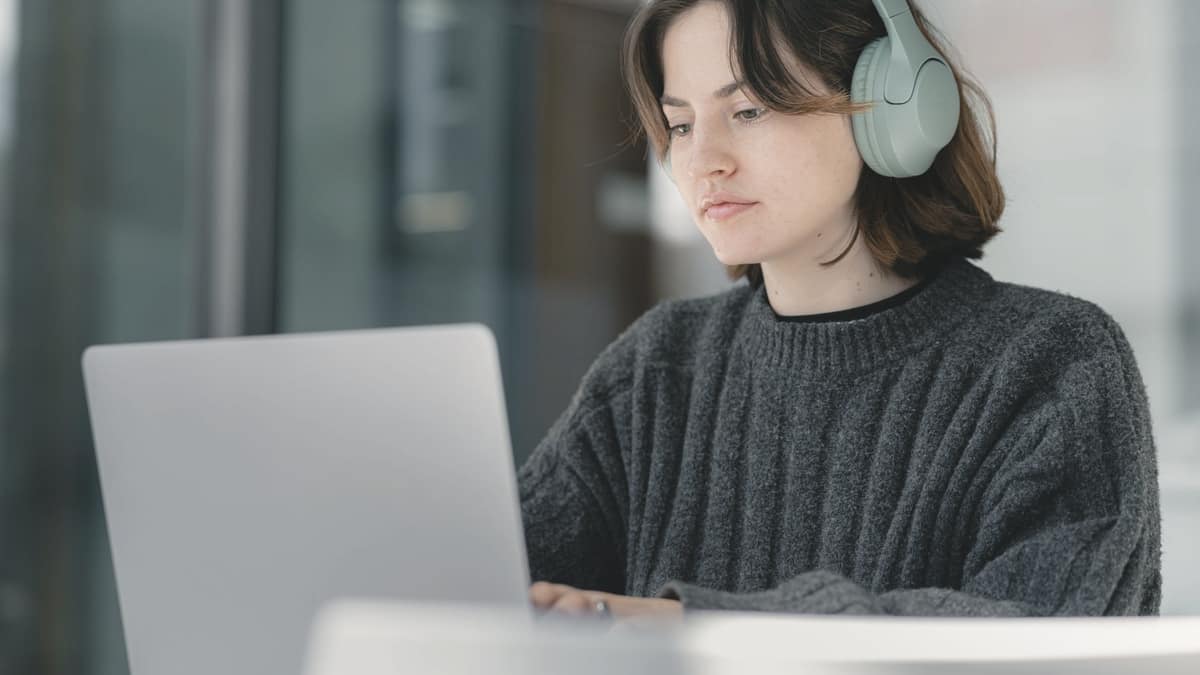 A person wearing headphones working at a laptop